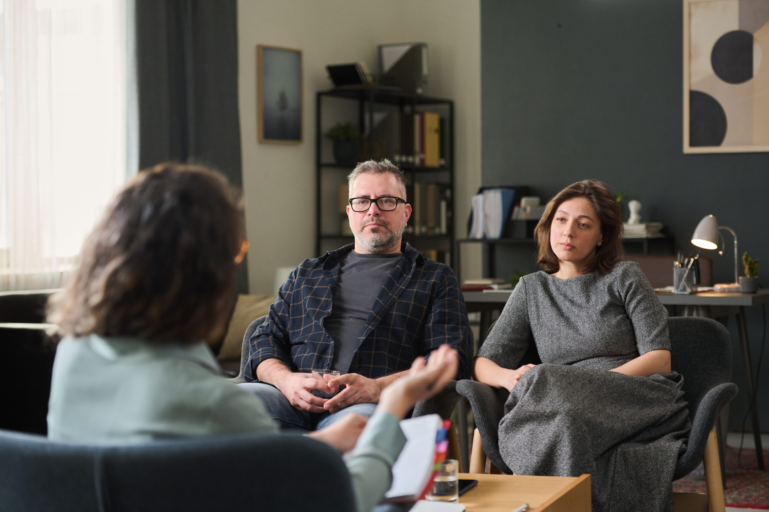 Couple sitting in office discussing relationship issues with therapist, specifically the affair that has come between them and the "messy middle" part that they're dealing with now.