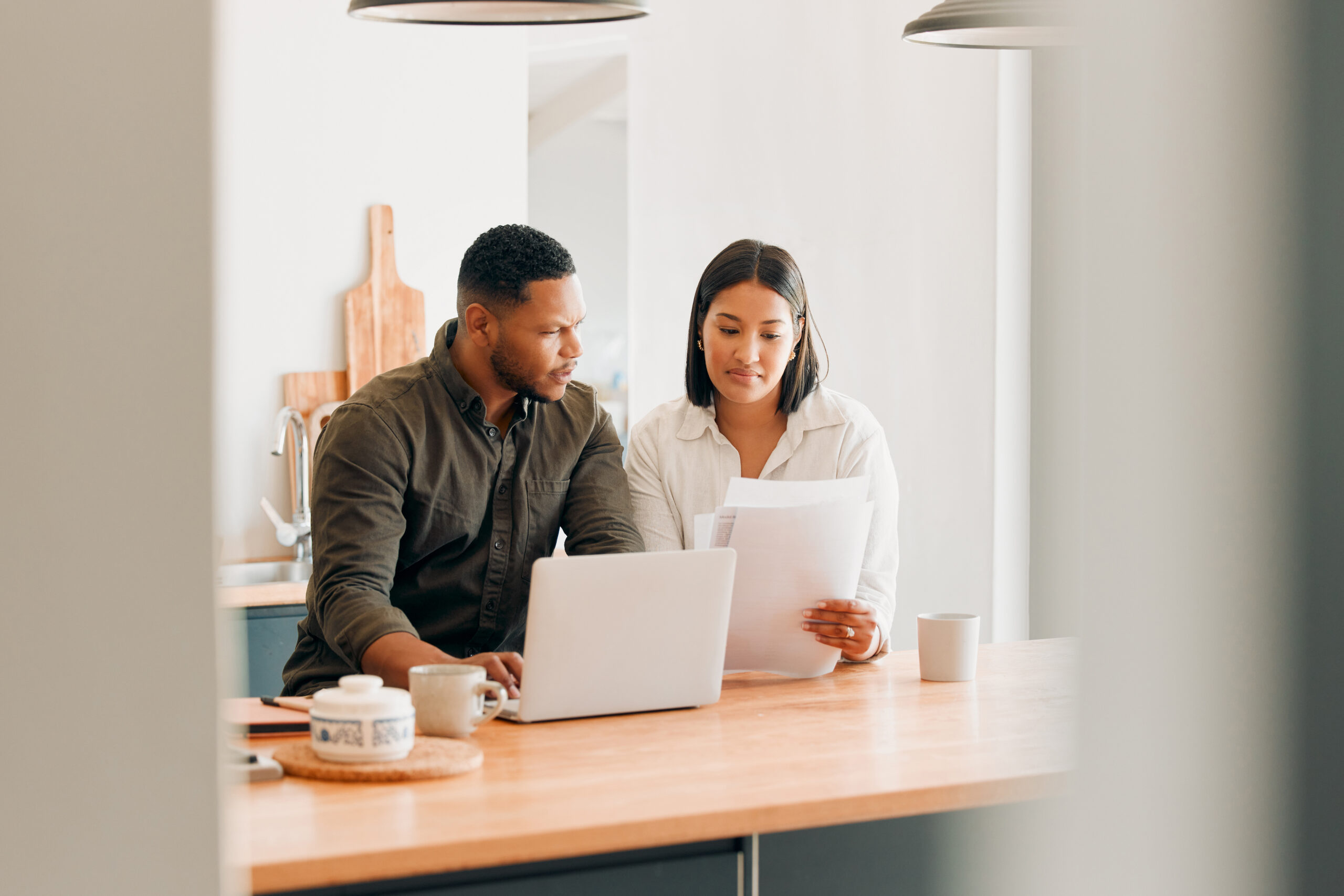 Couple reviewing financial documents together at home, discussing money and financial planning in their relationship.